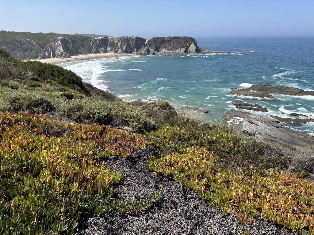 Praia dos Machados met begroeide rotsen op voorgrond