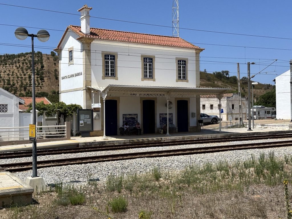 Wit stationsgebouw met rood dal en spoorlijnen ervoor in Santa Clara-Sabóia