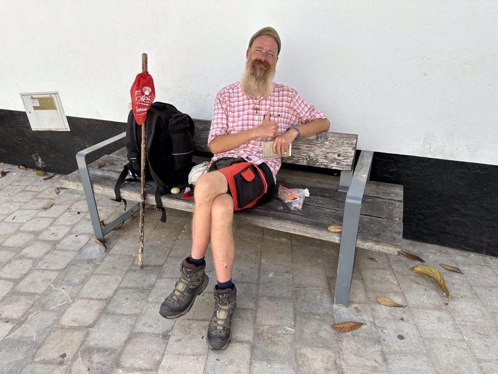 Pelgrim op bankje: rood-wit gestreept hemd, short, baard