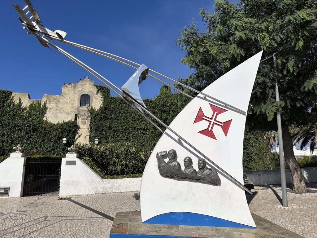 Monument voor drie piloten in de vorm van een wit zeil met afbeelding van de drie piloten;  Villanova de Milfontes