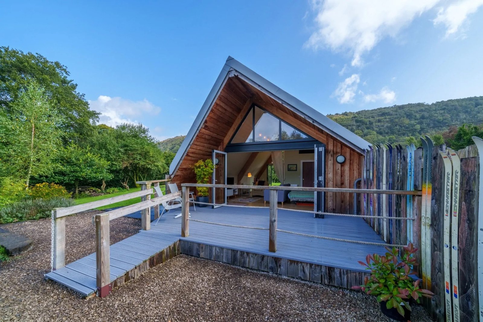 Houten huis met puntdak, langs één kant tot op de grond.