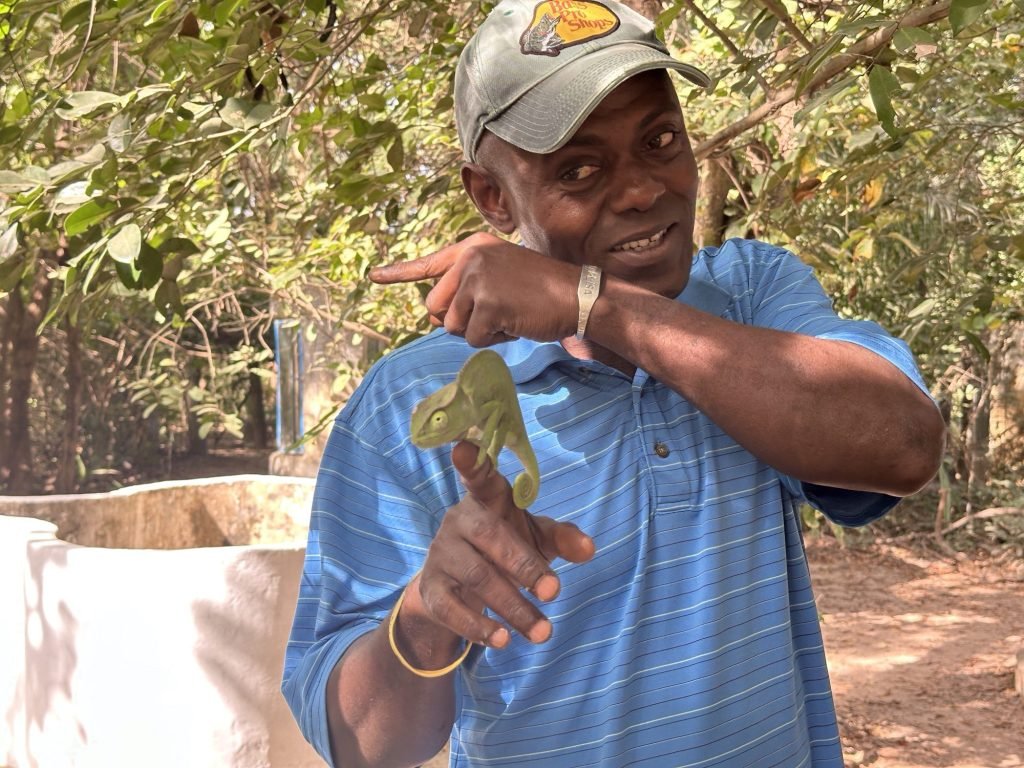 Snake man met blauwe T-sjirt en groene kameleon op zijn hand