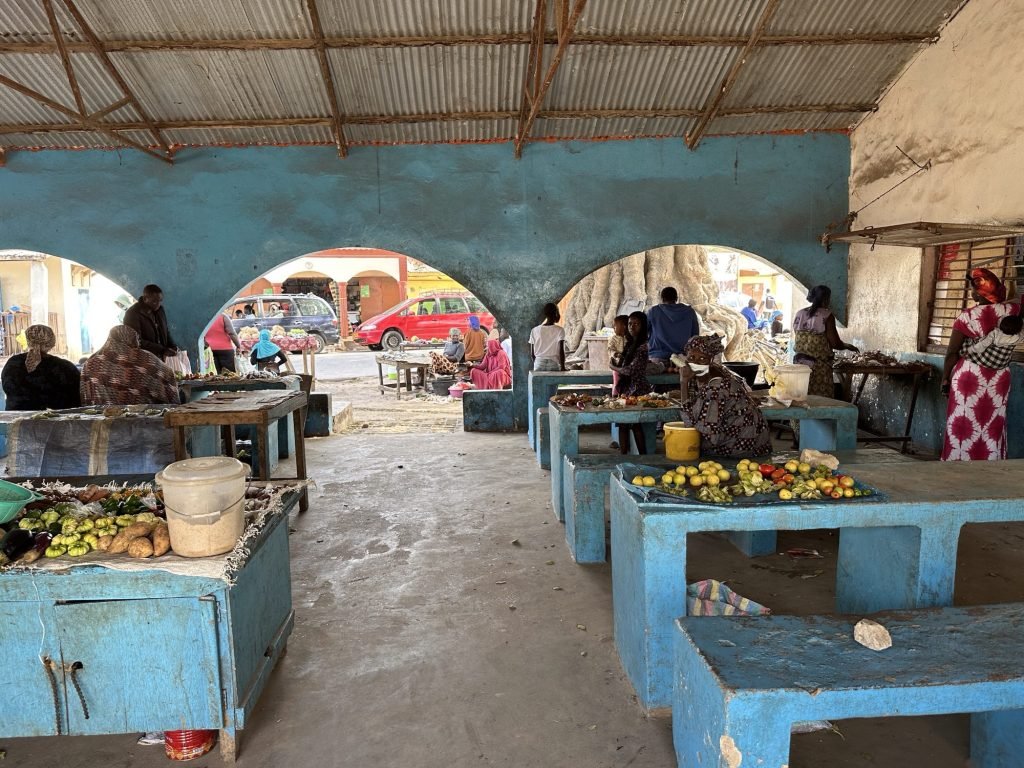 Binnenzicht Kartong markt met blauwe betonnen toonbanken en uitgestalde groenten en fruit