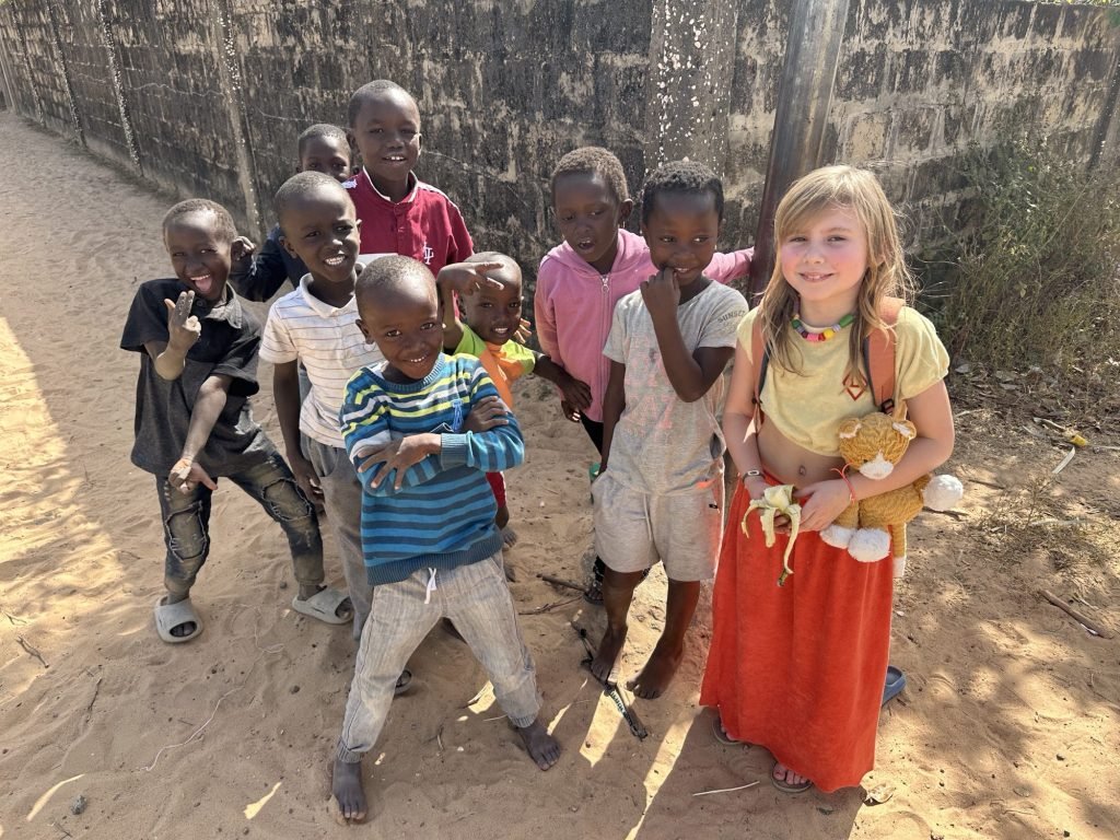 Acht kleine zwarte kinderen omringen wi, blond meisje met knuffelbeer
