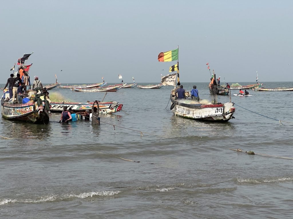Traditionele pirogues op zee net voor het strand met mensen die er naartoe waden