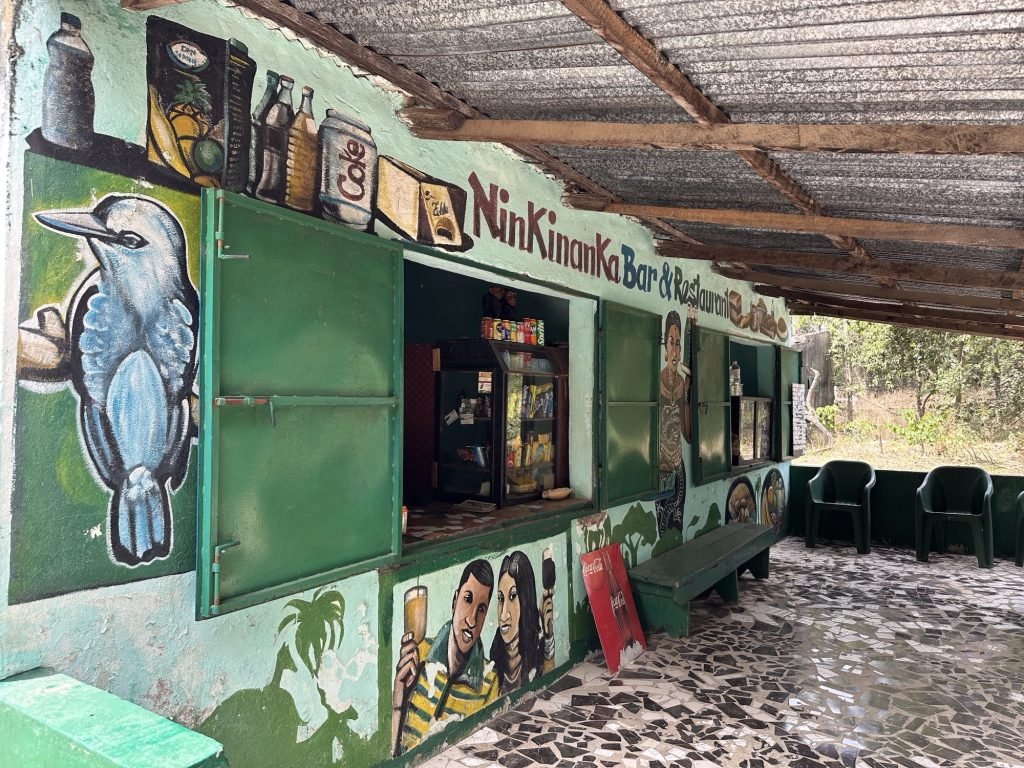 Bar, veelkleurig beschilderde met afbeelding van kingfisher en mensen in Abuko