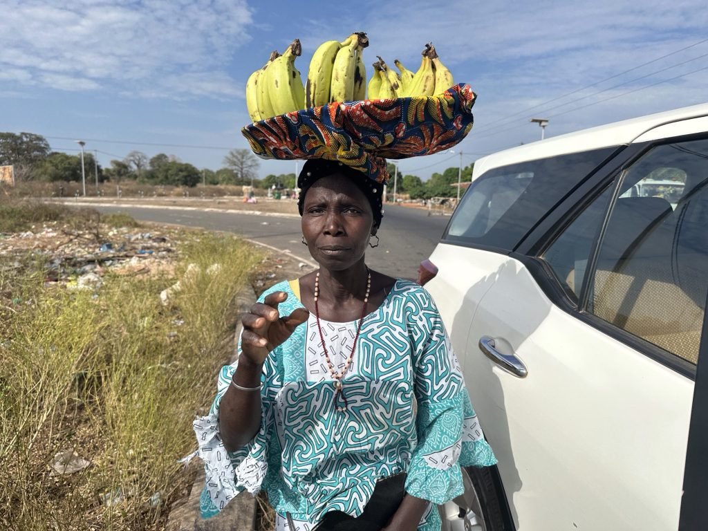 Zambiaanse in licht-blauw kleed met mand bananen op het hoofd