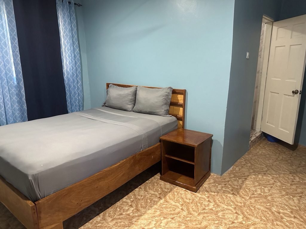 Spartaans uitziend interieur in Riverside Lodge: bed en lichtblauwe miren
