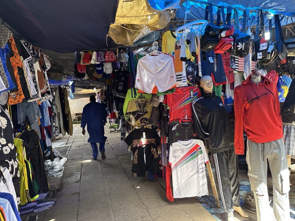 Heel smal straatje tussen hangende kleren in Albert Market. 