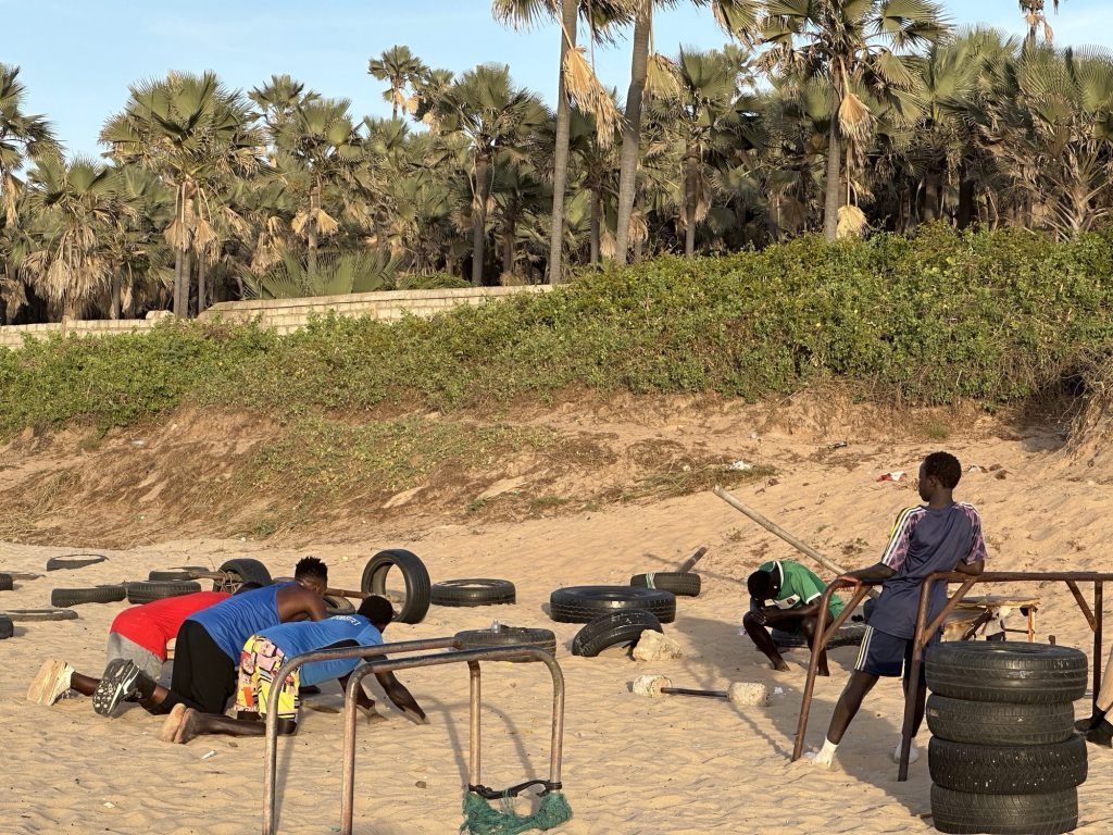 Drie mannen doen aan fitness op strand met autobanden