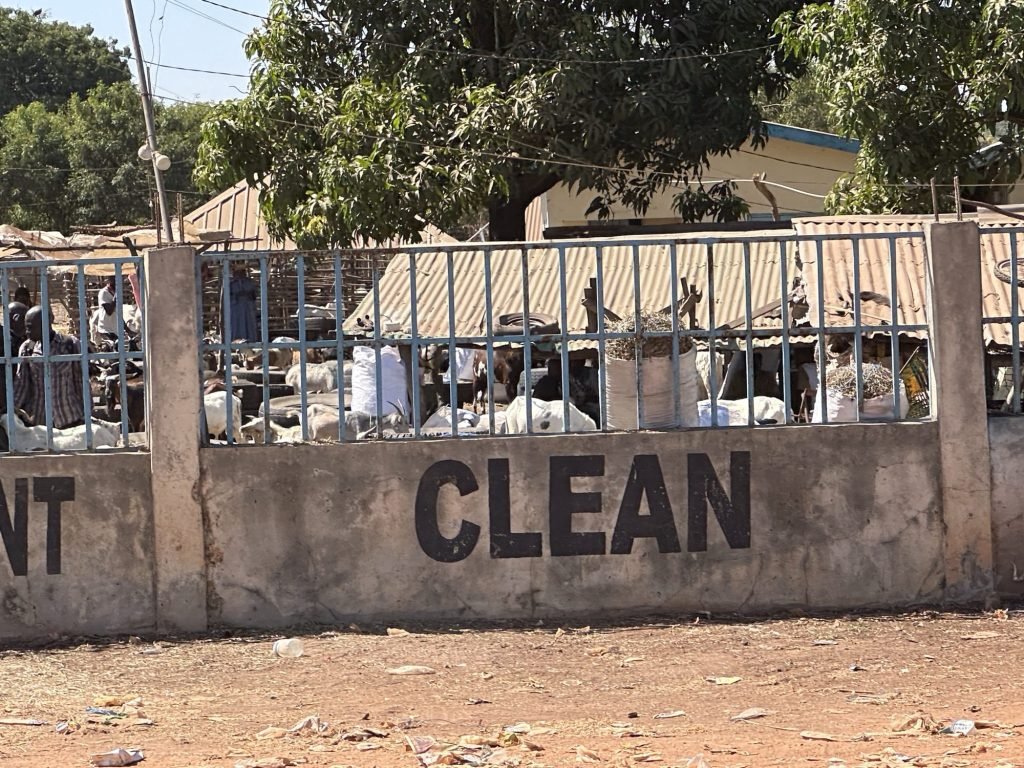 De veemarkt van Brikama met het woord “CLEAN” in grote letters op de muur