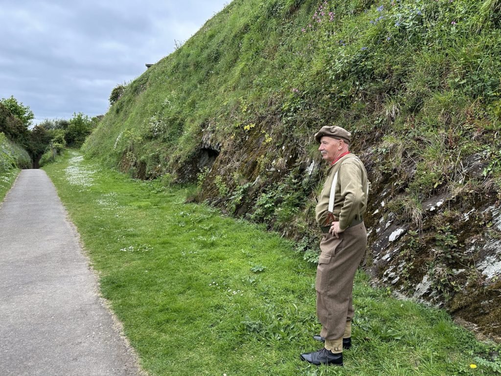 Gids in soldatenuniform uit WO II  in een diepe gracht in Pendennis Castle