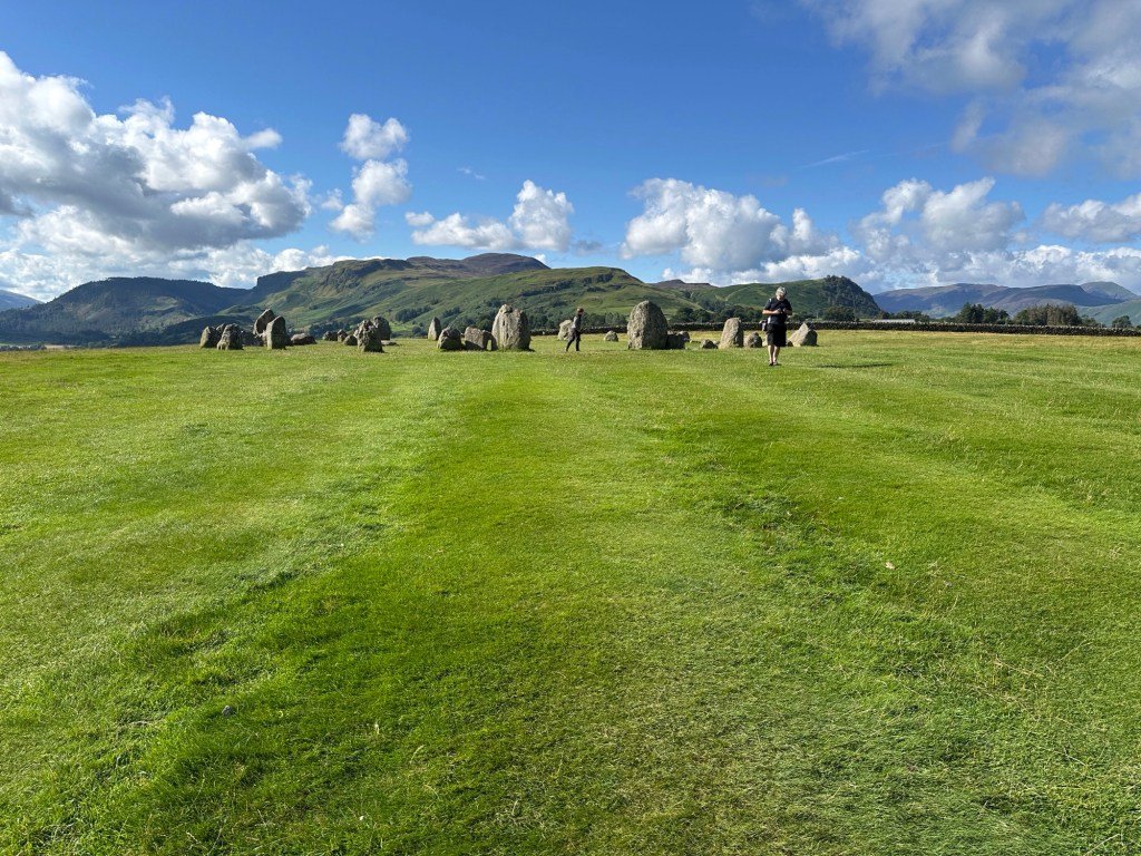 Grasveld, steencirkel en bergen. 