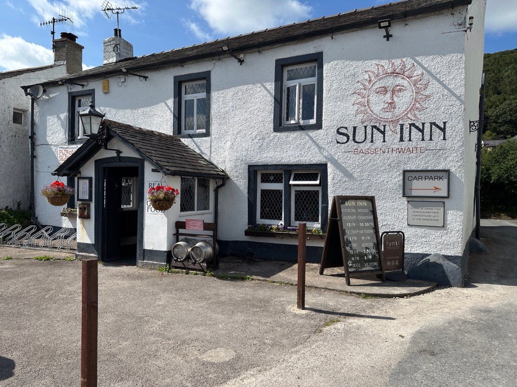 Witte gevel van Sun Inn met opschrift en tekening van zon. 