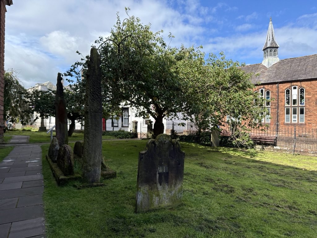 Kerkhof met oude graven en twee overblijfselen van hoge stenen kruisen.  
