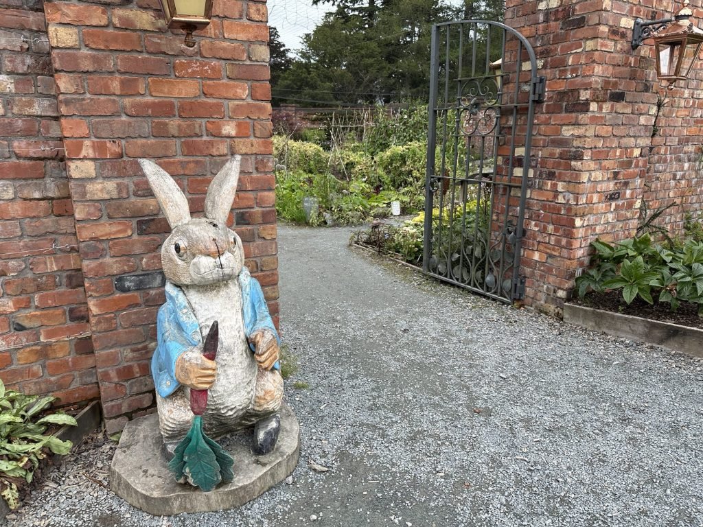Beeld van Peter Rabbit aan ingang van tuin. 
