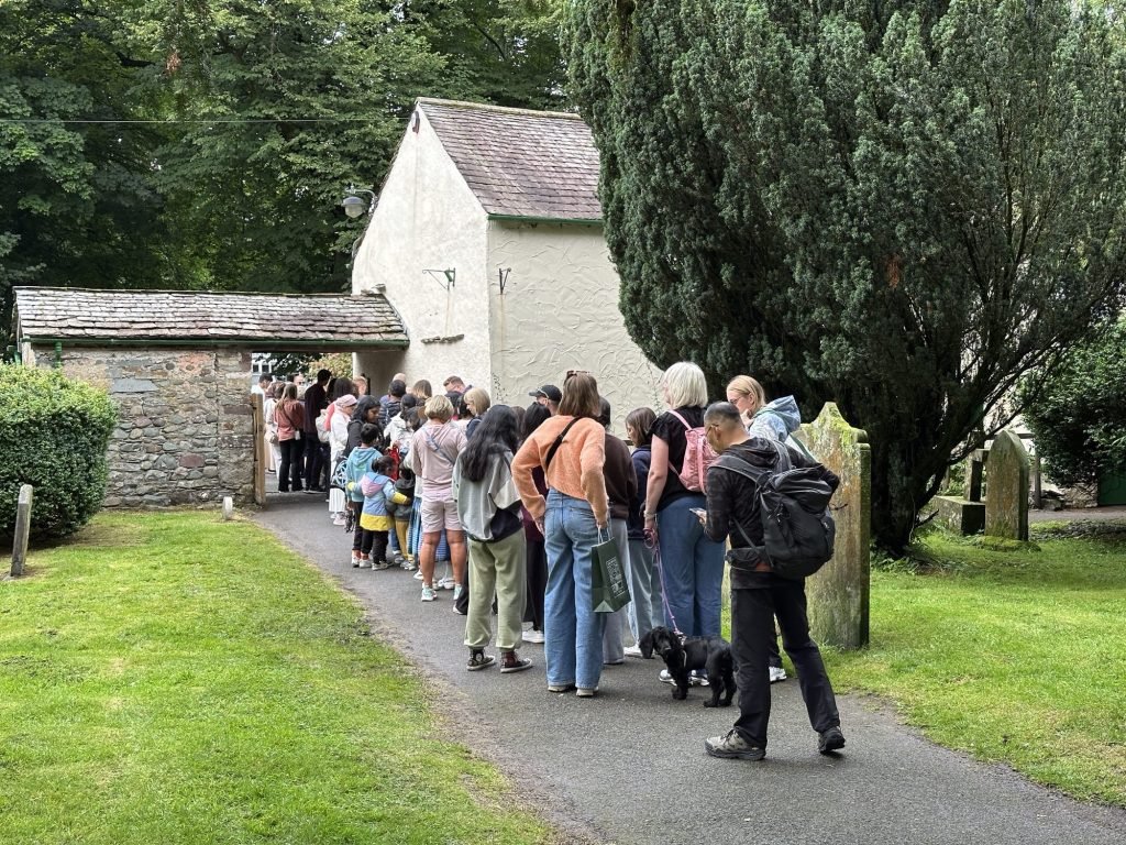 Mensen schuiven aan voor witte Dove Cottage. 