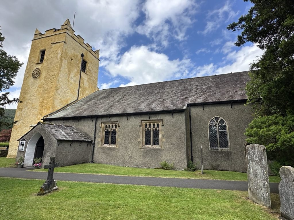 Grijze kerk met okergele toren van Grasmere. 