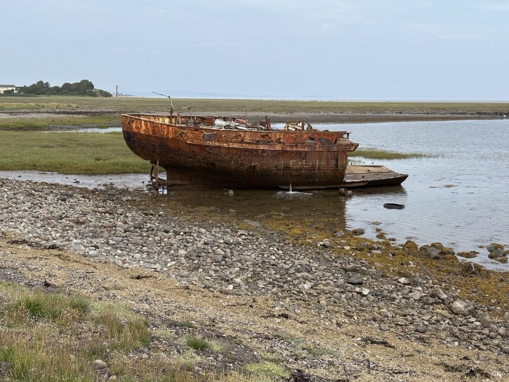 Roestig wrak van boot bij eb.