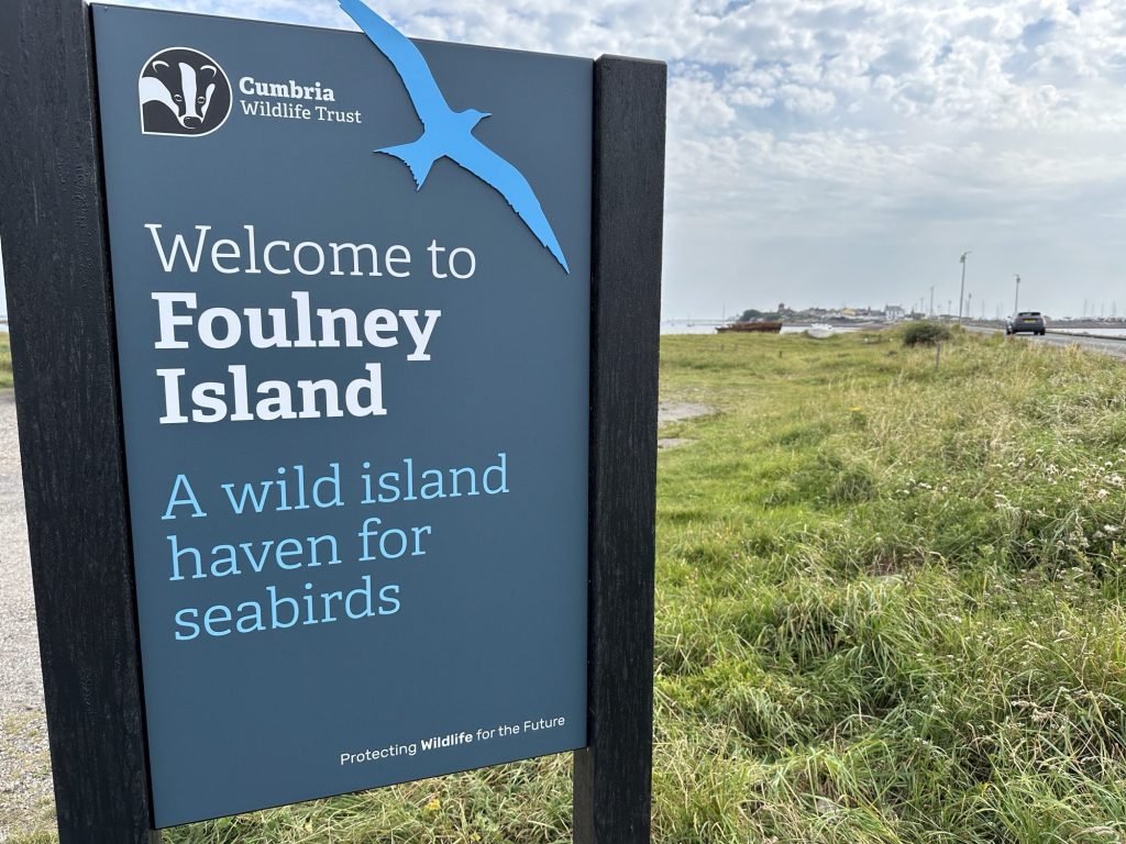 Welkomstbord van Foulney Island met groene grasstrook.