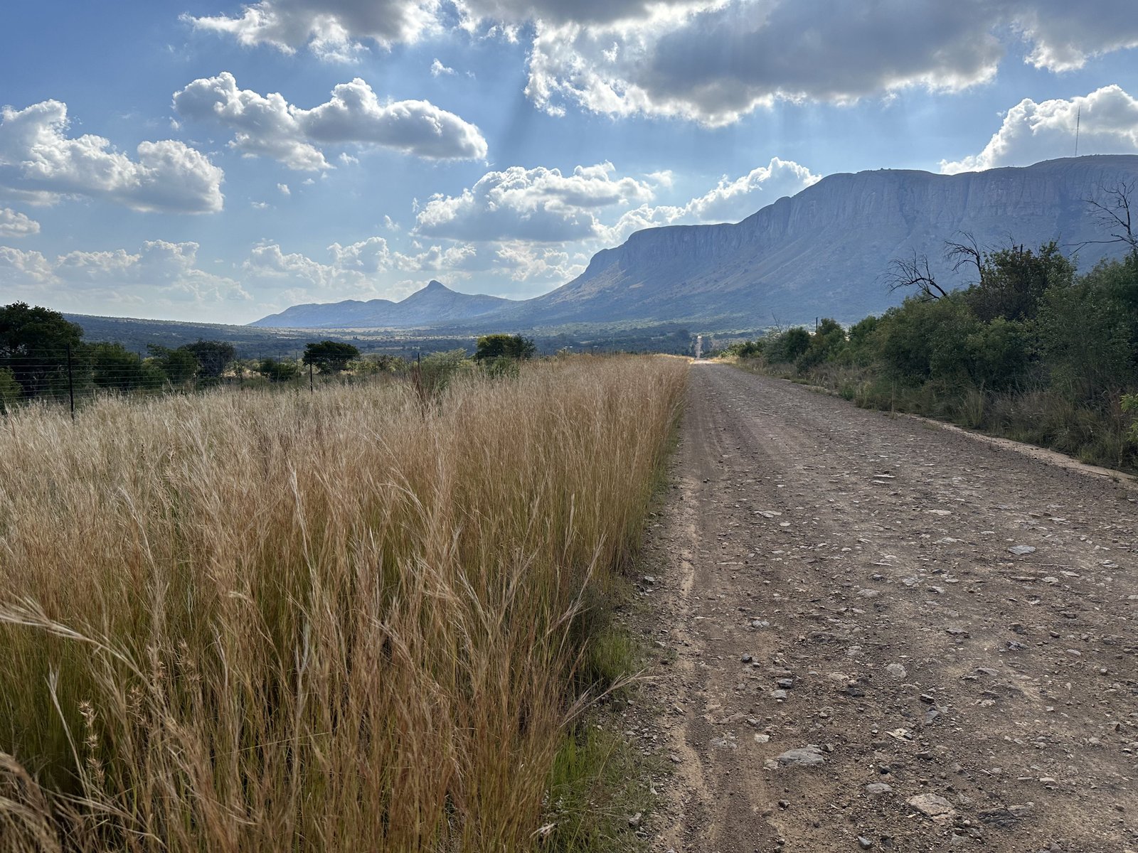 Thabazimbi road to Kololo: berglandschap met grindweg en wolken.