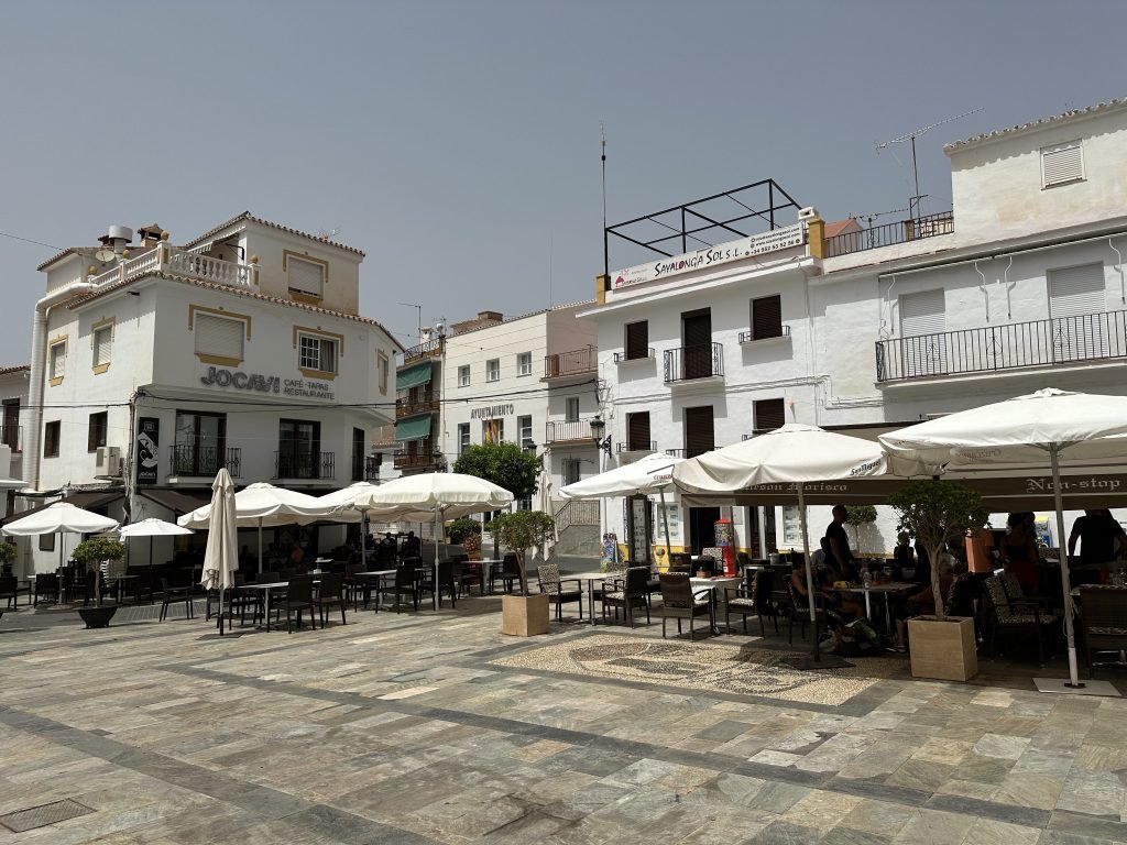 Sayalonga dorpsplein: witte huizen, witte parasols. 