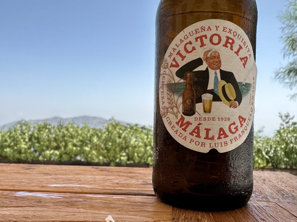 Fles Victoria-bier met etiket in close-up en warzige achtergrond van groen en bergen. 
