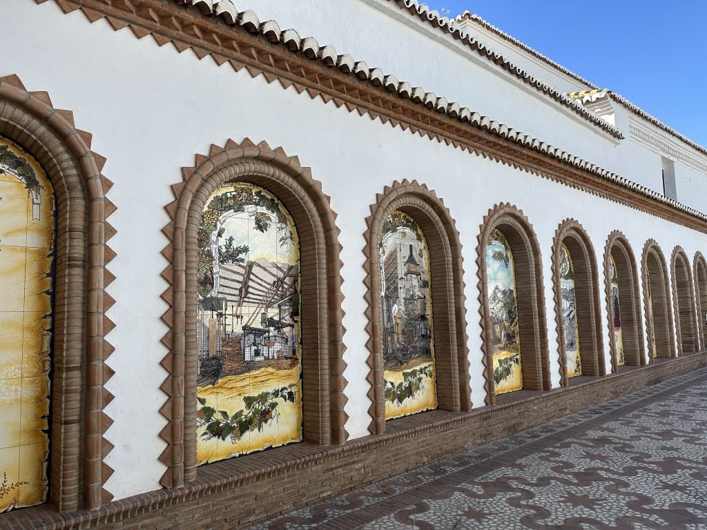 Paseo de las Tradiciones: grote mozaïeken in boogvormige inhammen in witte muur.  