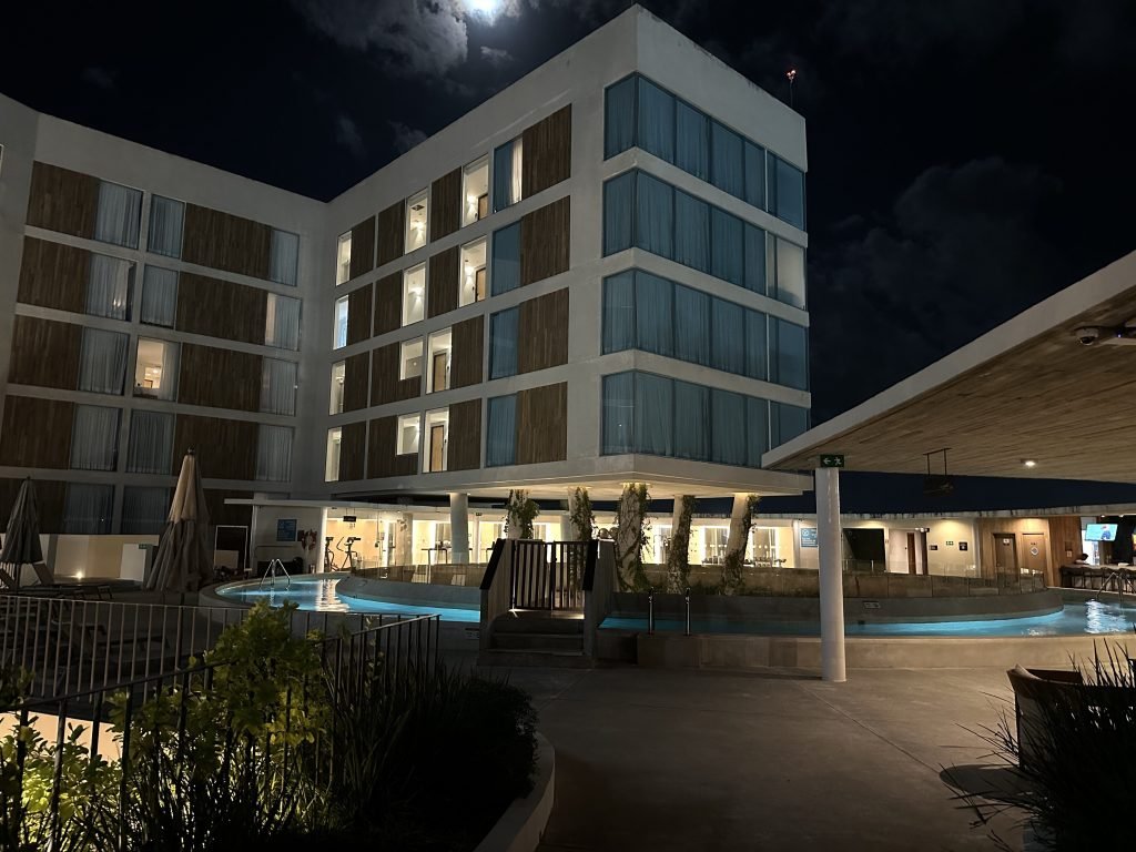 Verlicht vijf verdiepingen hoog gebouw van de Hilton Garden Inn Cancún Airport ‘s nachts. 