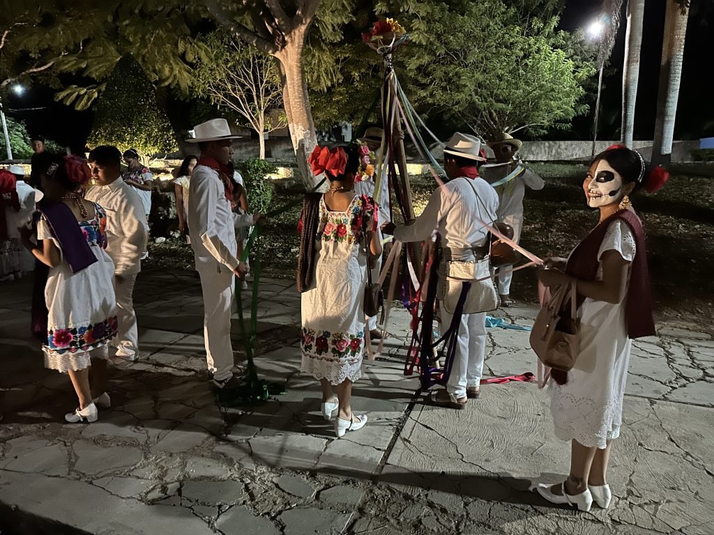 Mexicanen in traditionele klederdracht en wit beschilderde gezichten voor de día de muertos ‘s avonds. 