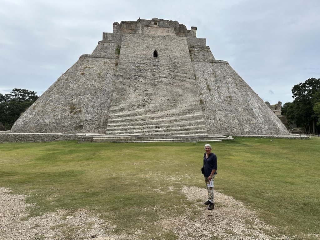 Grasveld met één toeriste en heel grote trap-piramide.