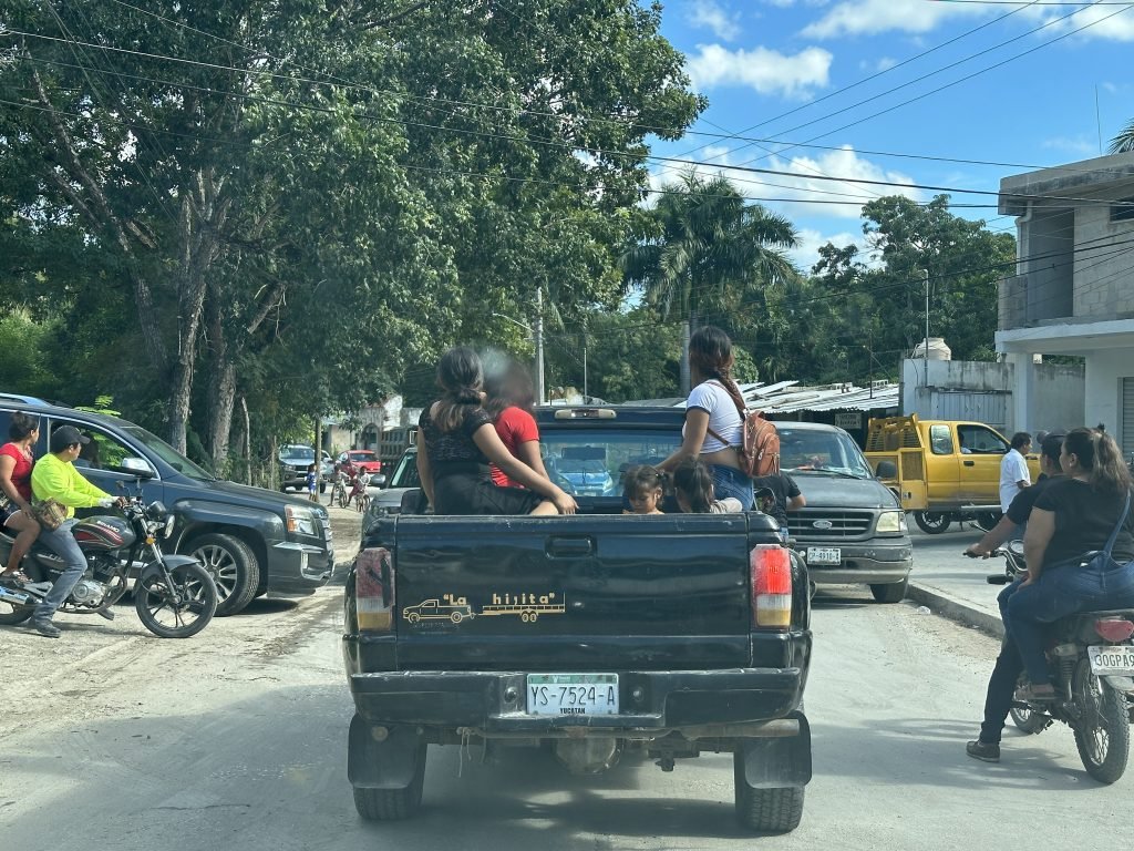 Verkeersopstopping in Chiná, Yucatan: Tieners in laadbak van truck. 