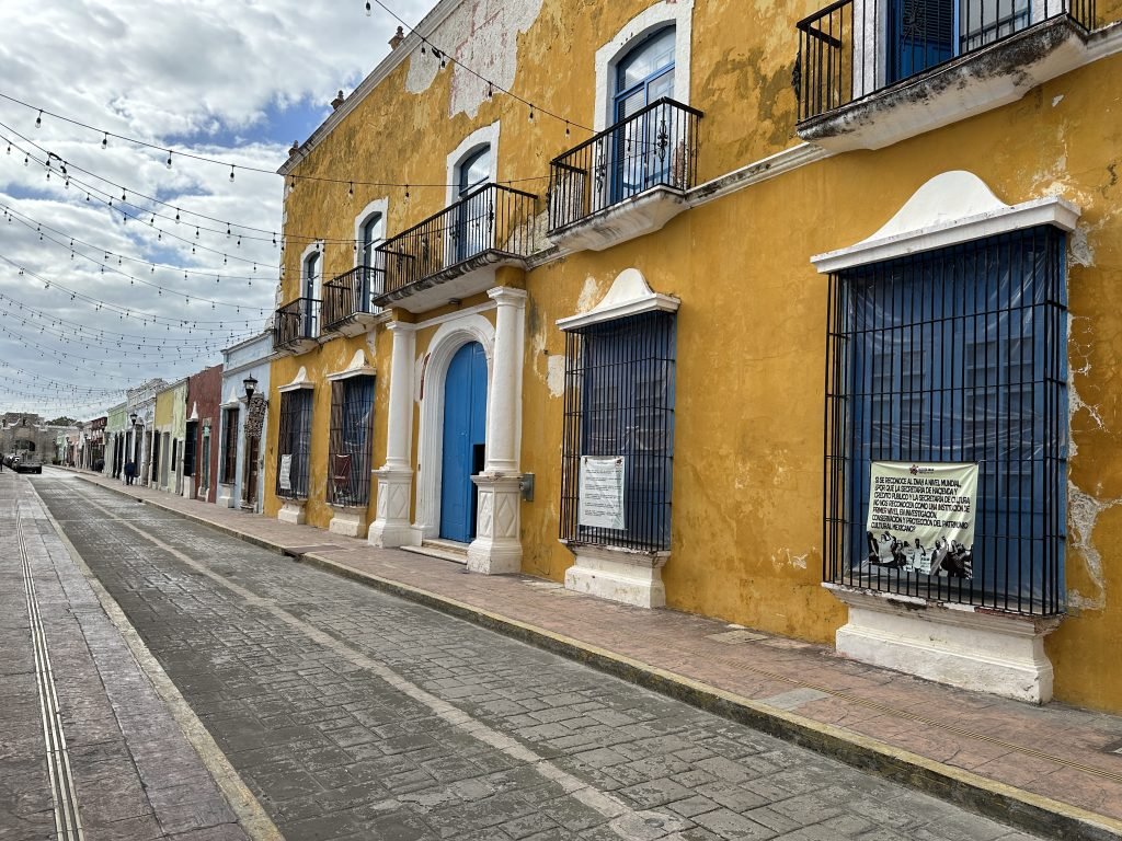Statig okergeel huis met blauwe luiken in Campeche. 