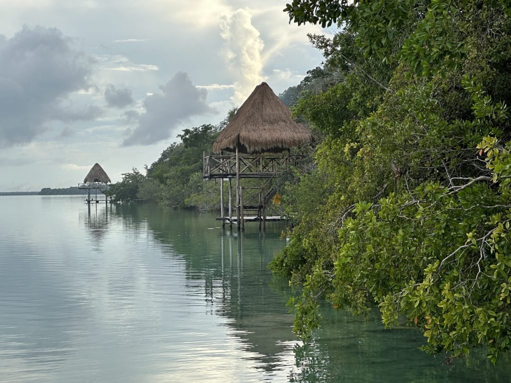 Begroeide oevers van Laguna Bacalar met twee steigers en hutjes. 